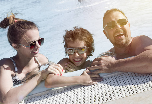 Onnellinen perhe uima-altaassa, hauskaa vedessä, äiti, jolla on kolme lasta, jotka nauttivat vesipuistosta, rantalomakeskuksesta, kesälomista, lomakonseptista
 - Valokuva, kuva