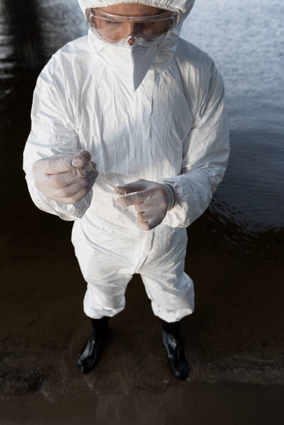 nehirde su örneği alan koruyucu kostümlü su denetçisinin yüksek açı görünümü - Fotoğraf, Görsel