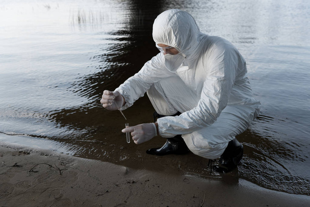 vízfelügyelő védőöltözet és légzőeszköz a vízminta szedését a folyónál - Fotó, kép