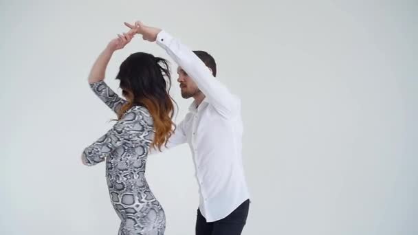 Η έννοια της αγάπης, των σχέσεων και του κοινωνικού χορού. Νεαρό όμορφο ζευγάρι χορεύει αισθησιακό χορό σε λευκό φόντο - Πλάνα, βίντεο