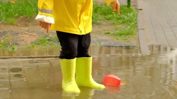 Маленький ребенок в ярко-желтых резиновых сапогах брызгает в лужу. Дети ноги защищены от грязной воды
 - Кадры, видео