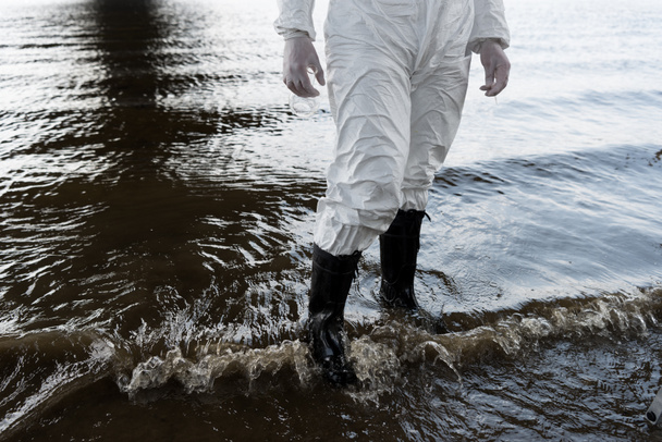 vista parziale dell'ispettore dell'acqua in costume protettivo e stivali in piedi nel fiume
 - Foto, immagini