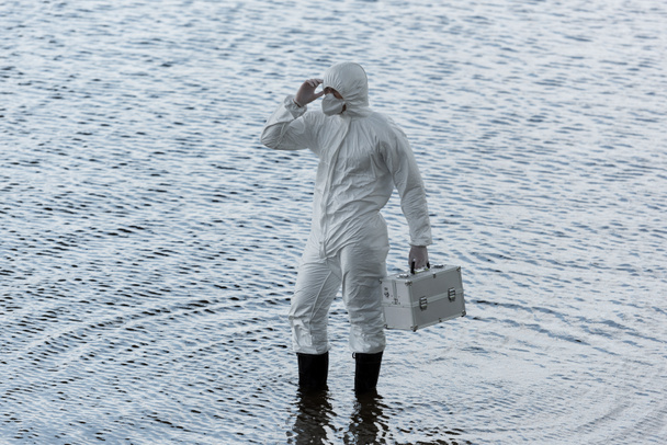 water inspector in protective costume holding inspection kit in river - Photo, Image