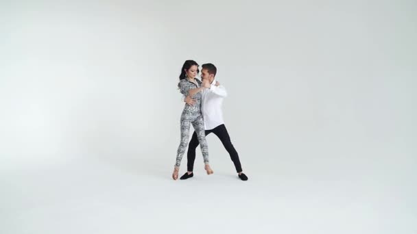 Concept of love, relationships and social dancing. Young beautiful couple dancing sensual dance on a white background - Footage, Video