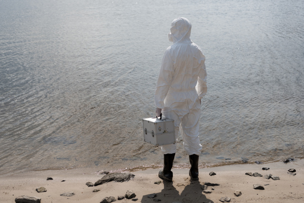 vista posteriore di ispettore dell'acqua in costume protettivo tenuta kit di ispezione sulla costa del fiume
 - Foto, immagini