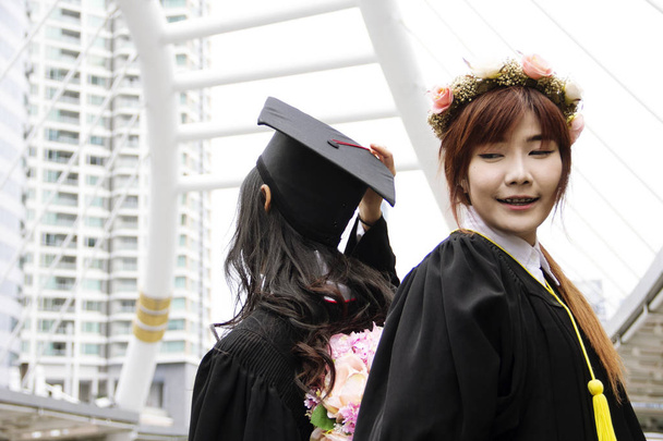Красивые выпускники аспирантуры две азиатки улыбаются и счастливы после окончания школы
. - Фото, изображение