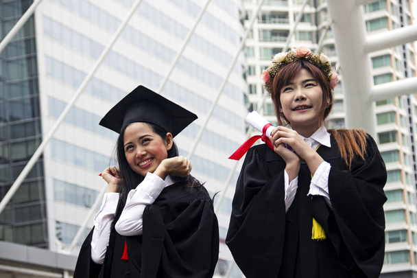 Gyönyörű végzős diplomások két ázsiai nő mosoly, és boldogok a diploma megszerzése után. - Fotó, kép