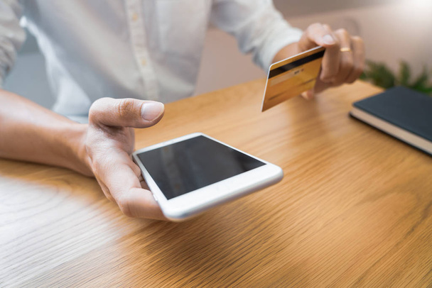 Mano del hombre en camisa casual pagando con tarjeta de crédito y usando sm
 - Foto, imagen