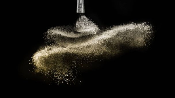 Cosmetic brush with golden cosmetic powder spreading for makeup  - Photo, Image