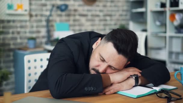 Middle-aged brunet sleeping at work putting head on table sitting at desk alone - Záběry, video