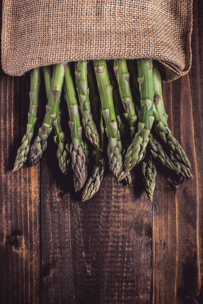 Raw Organic Asparagus in Juta Bag on Dark Wood Background - Foto, Bild