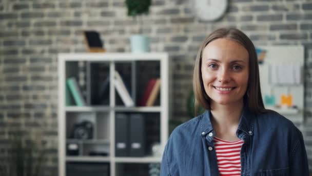 Portrait of joyful young lady smiling looking at camera standing in workplace - Filmagem, Vídeo