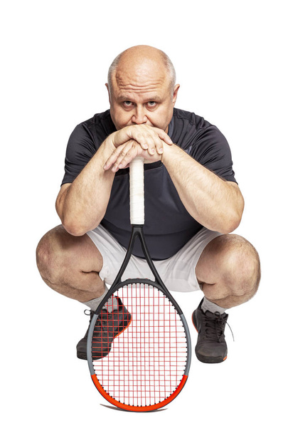 A bald middle-aged man with a tennis racket squats. Isolated on a white background. - Φωτογραφία, εικόνα