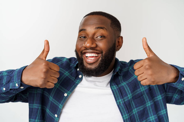 Portrait de heureux afro-américain bel homme barbu riant et montrant geste pouce vers le haut
. - Photo, image