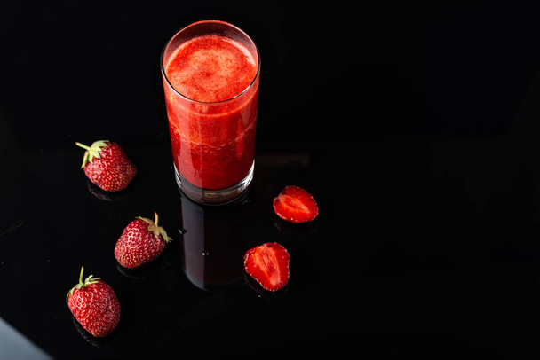 leckerer Erdbeer-Smoothie auf schwarzem Hintergrund. - Foto, Bild