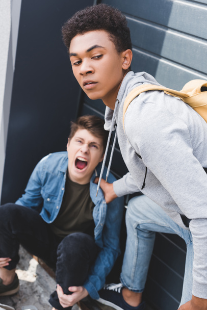 selective focus of african american boy in hoodie and jeans bulling screaming and scared boy - Fotoğraf, Görsel