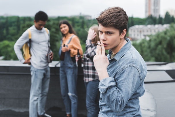 foco seletivo de adolescente fumar cigarro e olhando para longe
  - Foto, Imagem