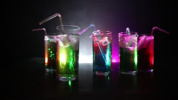 Vijf cocktails op de balk met rook op donkere achtergrond. Geel, groen en blauw gekleurde glazen. - Video
