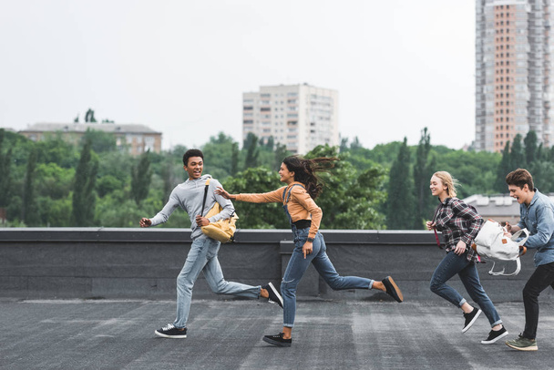 playful and happy teenagers running on roof and smiling  - Fotó, kép