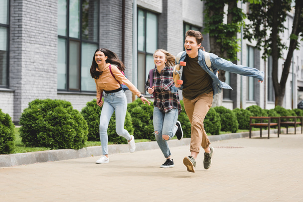 hravé a šťastné Teenageři běžícím se skateboard a usmívajícími se  - Fotografie, Obrázek