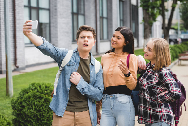 adolescentes felices sosteniendo el teléfono inteligente, tomando selfie y sonriendo
  - Foto, Imagen