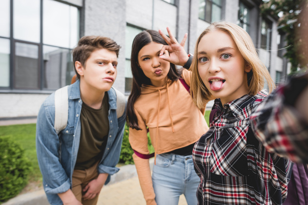 positive teenagers taking selfie and showing ok gesture outside  - 写真・画像
