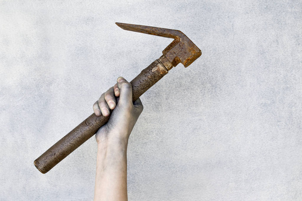 Hand holding old rusty hammer on gray background. - Foto, imagen