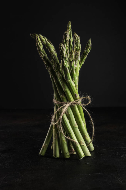 Green fresh asparagus on black wooden table. - Foto, afbeelding