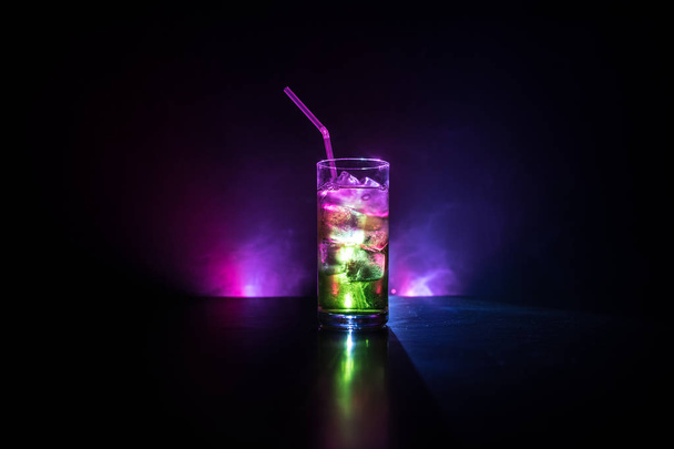 Verre à cocktail éclaboussant sur fond fumé teinté foncé ou cocktail coloré en verre. Soirées animées. Lumière mixte
. - Photo, image
