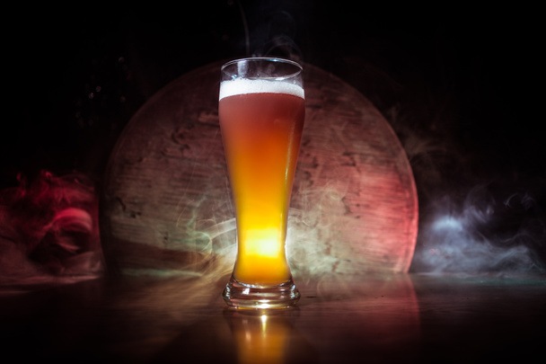 Creative concept. Beer glasses on wooden table at dark toned foggy background. - Photo, Image