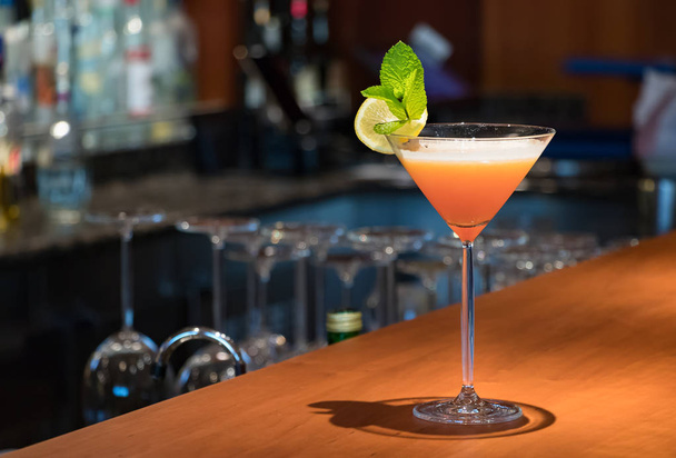 A orange color Martini drink on a wooden bar counter. - Foto, immagini
