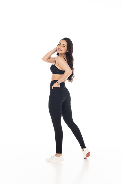 full length view of smiling sexy girl in black bra and pants with hand in pocket isolated on white - Zdjęcie, obraz