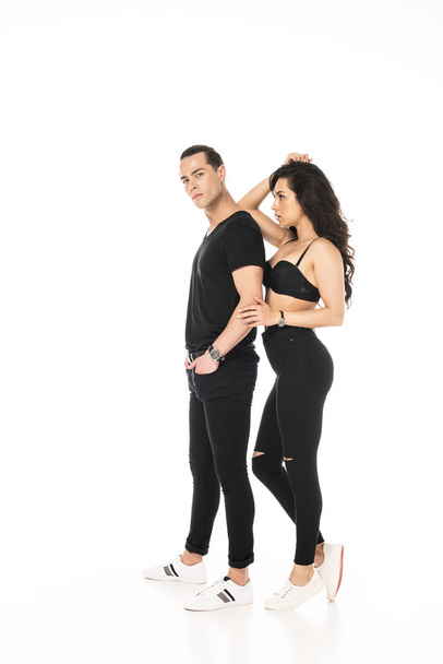 volledige lengte weergave van de mens met de hand in zak en sexy meisje in zwarte beha geïsoleerd op wit - Foto, afbeelding