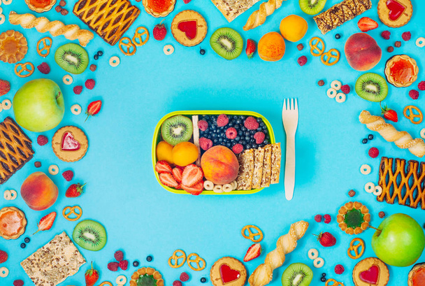 Kehys eväslaatikko ja paljon hedelmiä, marjoja ja crunches päälle - Valokuva, kuva