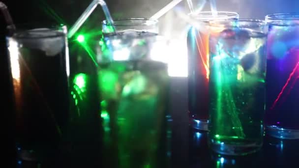 Pět koktejlů v baru s kouře na tmavém pozadí. Žluté, zelené a modré barevné brýle. - Záběry, video