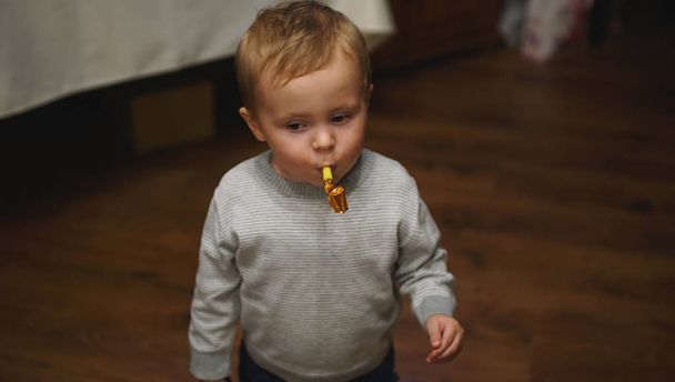 Симпатичний хлопчик дме партійний ріг під час вечірки на день народження в кафе
 - Фото, зображення