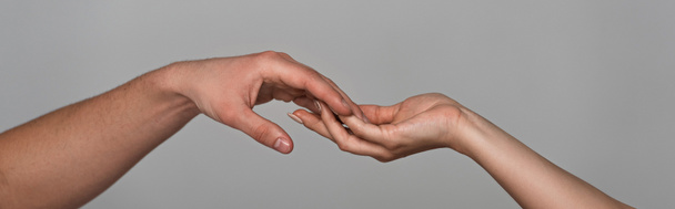panoramic shot of young couple touching hands isolated on grey - Foto, afbeelding