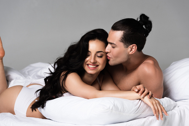 σέξι γδύσιμο ζευγάρι χαμογελά ενώ ξαπλωμένοι στο κρεβάτι μαζί - Φωτογραφία, εικόνα
