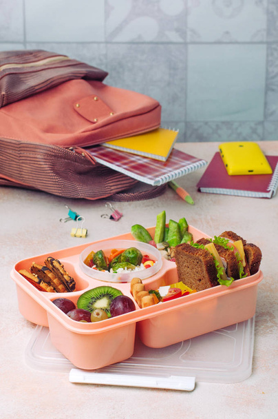 Lunch box on the table near school or student backpack - Φωτογραφία, εικόνα