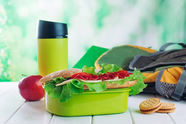 Caixa de almoço com sanduíche perto de biscoitos, caneca térmica e ba escolar - Foto, Imagem