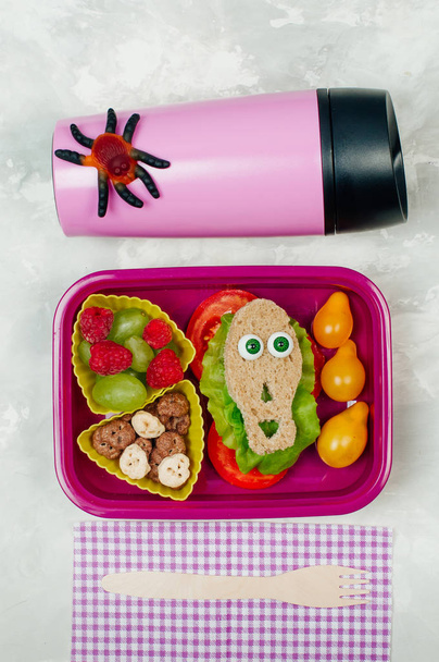 Open Halloween lunch box with school lunch with near thermo mug.  - Foto, Imagen