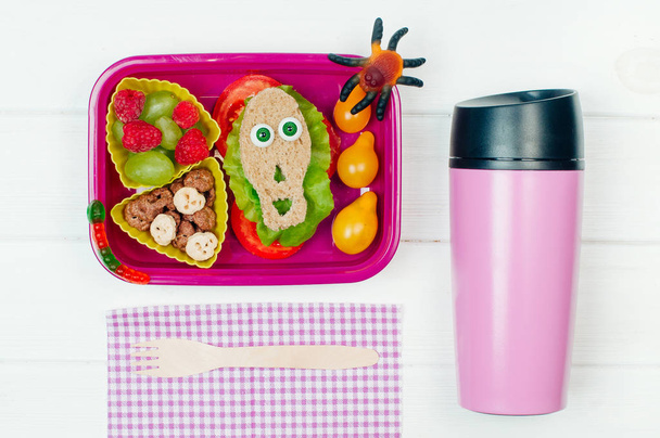 Open Halloween lunchbox met schoollunch op witte houten achterkant - Foto, afbeelding