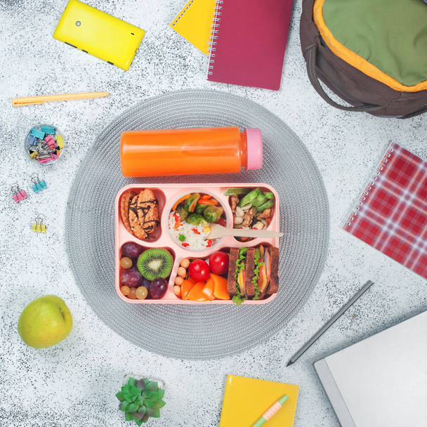 Boîte à lunch ouverte avec des aliments sains sur le fond gris avec sch - Photo, image