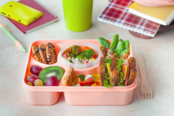 Відкрита обідня коробка зі здоровим обідом на офісному столі біля рюкзака
  - Фото, зображення