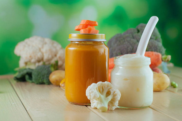 Two jars with carrot, pumpkin and cauliflower puree near fresh v - Фото, зображення