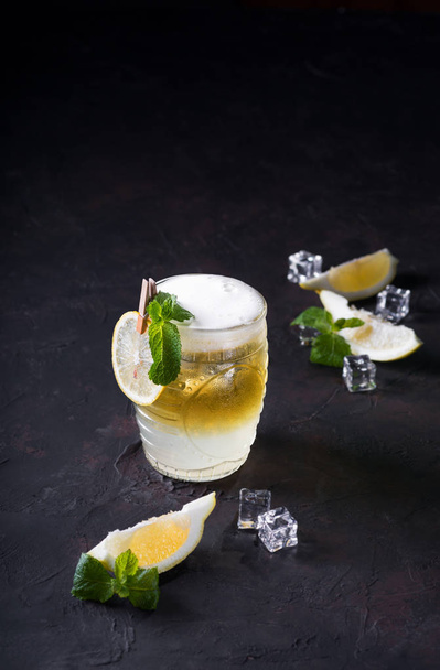 Moscow Mule cocktail op een donkere achtergrond. Koud drankje, gelaagd wit en geel met wodka, kruidig Gemberbier en limoensap. Selectieve focus. Cocktail kaart - Foto, afbeelding