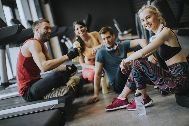 Группа молодых людей в спортивной одежде разговаривает в спортзале после тренировки
 - Фото, изображение
