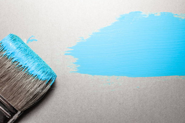 paint brush in blue paint on an unpainted flat surface, copyspace - Photo, Image