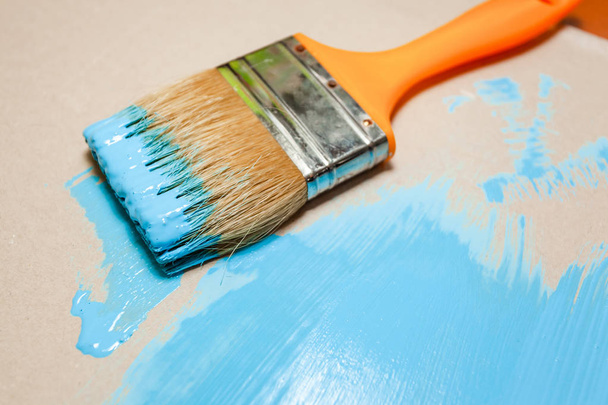 paint brush in blue paint on an unpainted flat surface - Photo, Image
