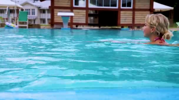 Beautiful girl in bikini swims in the pool outdoors. Rest in the mountains of Russia. Spa hotel in the forest area. - Video, Çekim
